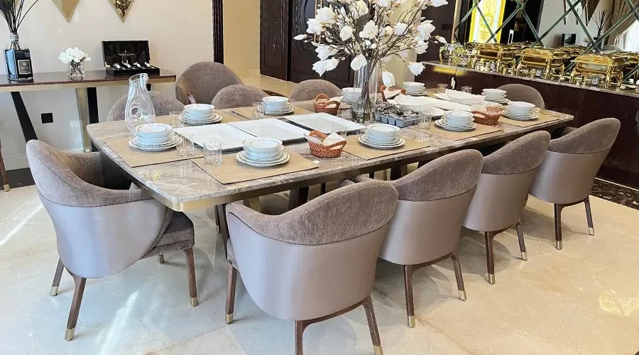Modern dining room design furniture featuring a luxury marble-top table and custom upholstered chairs in a classic elegant interior