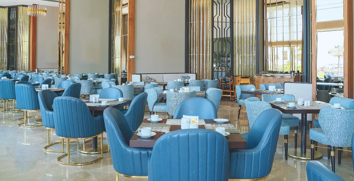 Luxury restaurant furniture with blue upholstered chairs and dark wooden tables in a modern dining setup – custom hospitality design by Bold Bespoke Design UAE.