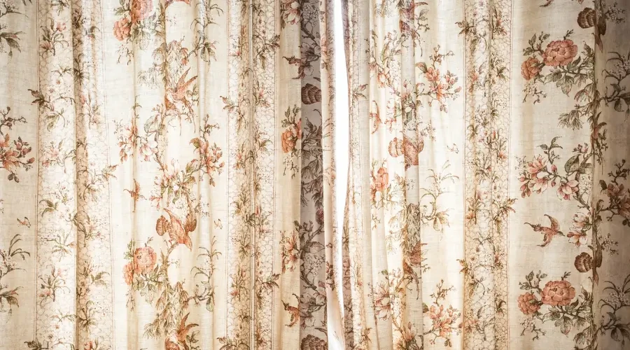 Classic floral patterned curtains featuring soft pastel hues of pink, orange, and green, adding a vintage charm and elegance to the space. The intricate design enhances the room with a warm, inviting atmosphere.