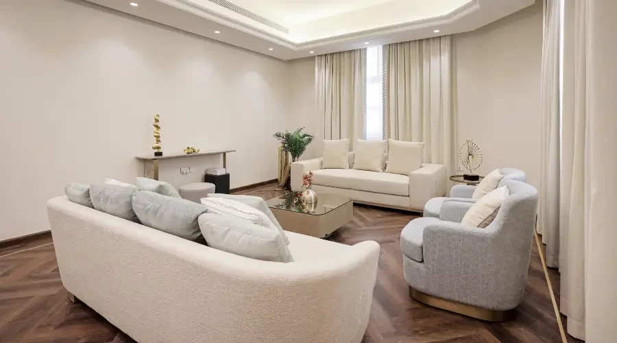  Modern living room furntiure- Abu Dhabi including Elegant living room featuring soft neutral-colored sofas, light curtains, and a modern coffee table, creating a cozy, minimalist vibe.