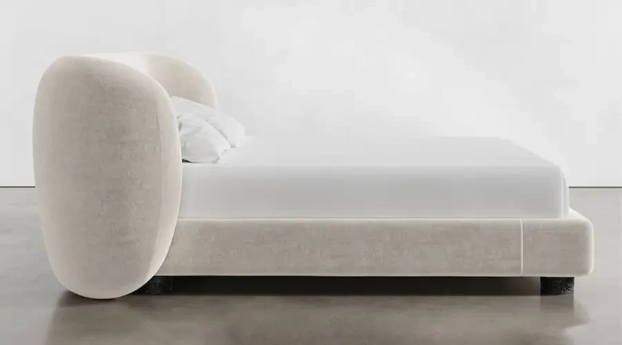 Luxury custom bed with a rounded, upholstered headboard and soft beige fabric, showcasing modern minimalist design.